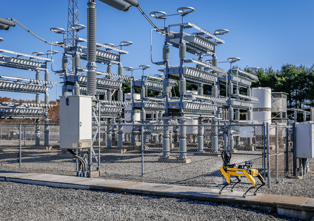 Yellow quadrupedal robot with National Grid logo walking around a power plant