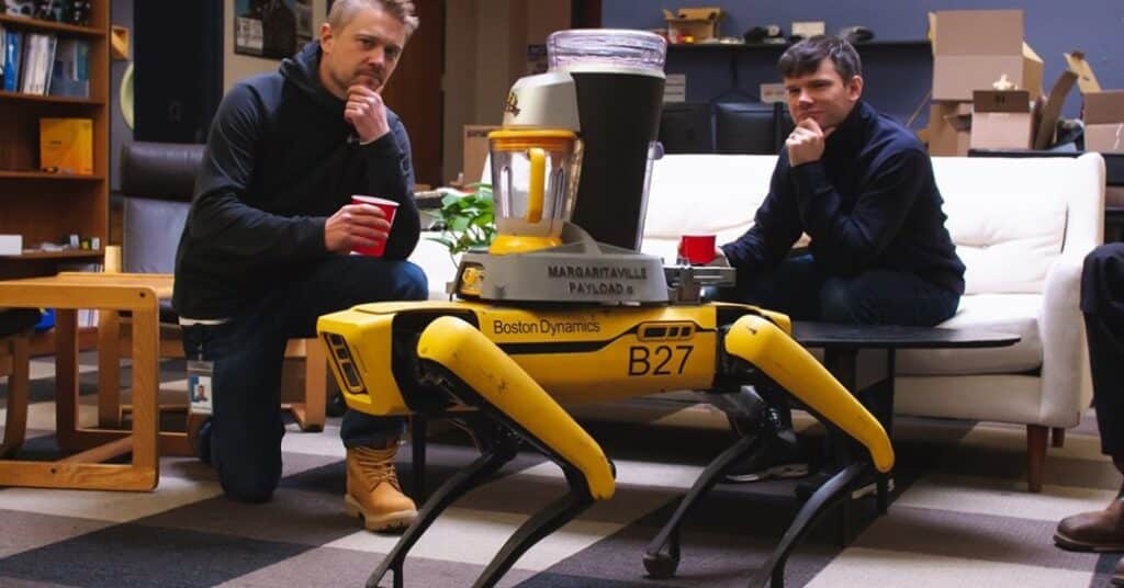 Two engineers pose next to Spot equipped with a margarita machine