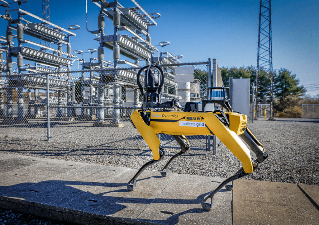 Yellow quadrupedal robot with National Grid logo standing outside a power plant