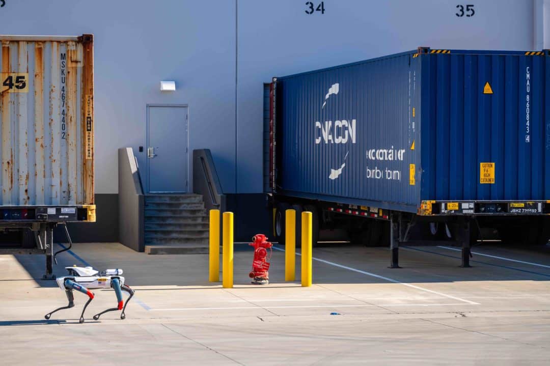 Spot walks past a trailer at a loading dock