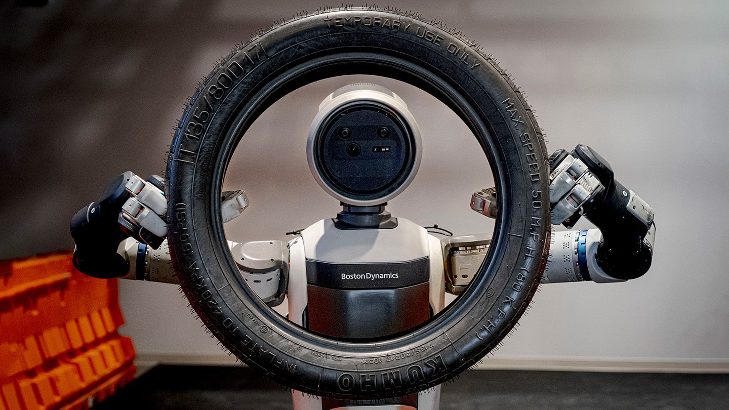 Boston Dynamics Atlas robot lifts a tire to head height, looking through the center