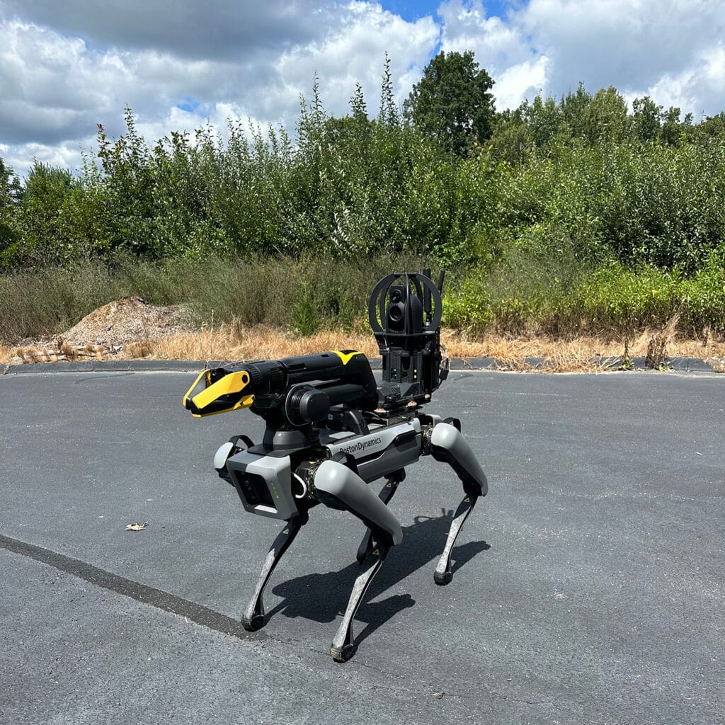 A gray Spot quadruped robot equipped with an arm and camera payload